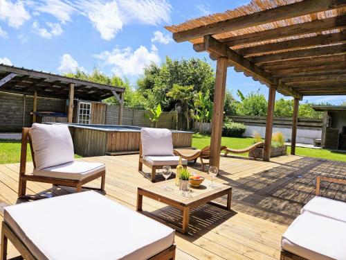 a wooden deck with chairs and a pergola at Spacieuse maison avec piscine, 9km de l'océan. in Tosse