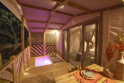 a small house with a wooden deck with a table at Le Lenze Don Mimì Glamping in Mattinata
