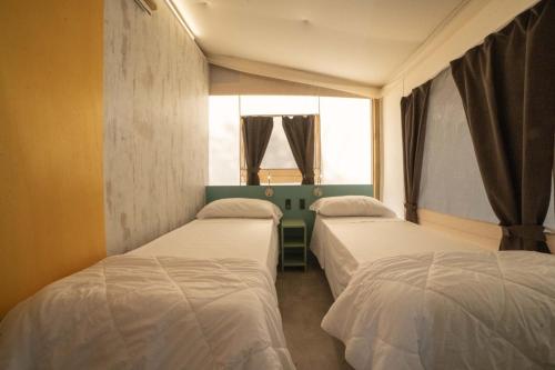 two beds in a room with a window at Le Lenze Don Mimì Glamping in Mattinata
