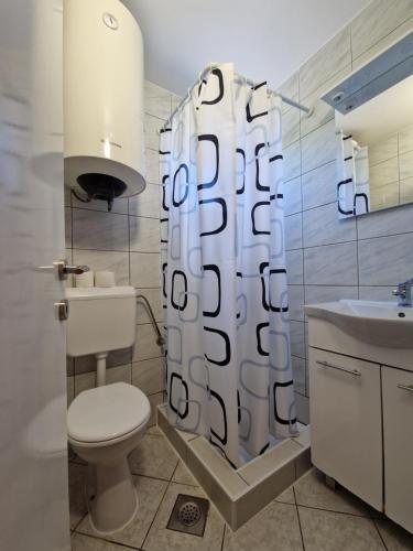 łazienka z toaletą i zasłoną prysznicową w obiekcie Pool Apartments Knežević Novalja w Novalji