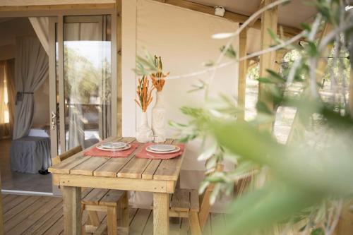 a wooden table with plates on it on a porch at Le Lenze Don Mimì Glamping in Mattinata