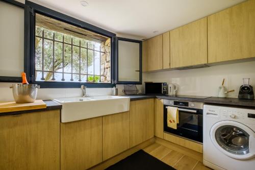 a kitchen with a sink and a washing machine at Villa Cyprès Bleu in Peymeinade