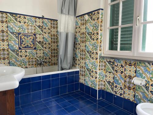 y baño de azulejos azules con ducha y lavamanos. en Villa Morena, en Cava deʼ Tirreni
