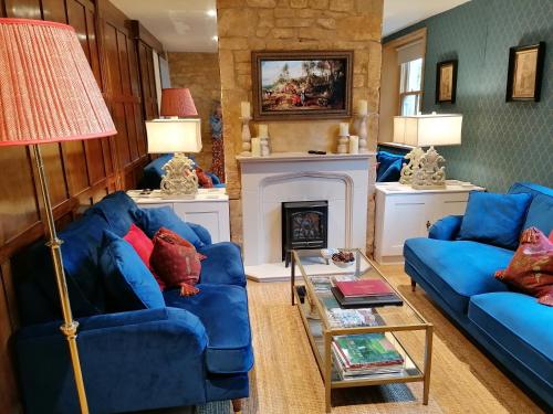 a living room with two blue couches and a fireplace at Merriman Cottage in Chipping Campden