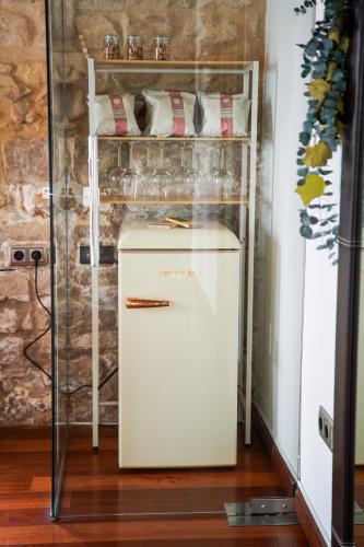 a small white refrigerator in a room with a shelf at Hotel Baeza Monumental by eme hoteles in Baeza