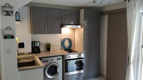une cuisine avec un lave-linge et un lave-linge dans l'établissement T2 avec jardin et terrasse au pied du mont Saint Martin à 400m du port, au Cap d'Agde
