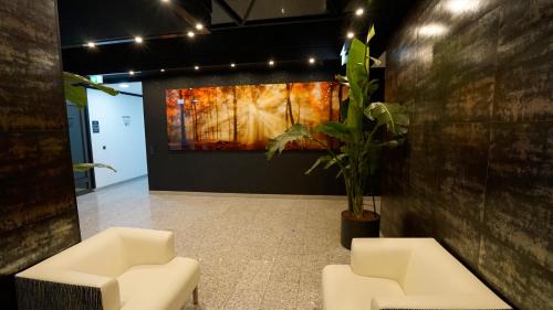 a room with two white chairs and a painting on the wall at TIBET HOTEL am Airport Düsseldorf-Ratingen in Ratingen