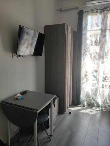 Cette chambre dispose d'une table, d'une télévision et d'une fenêtre. dans l'établissement Bienvenue sur la Cote d'Azur, à Nice