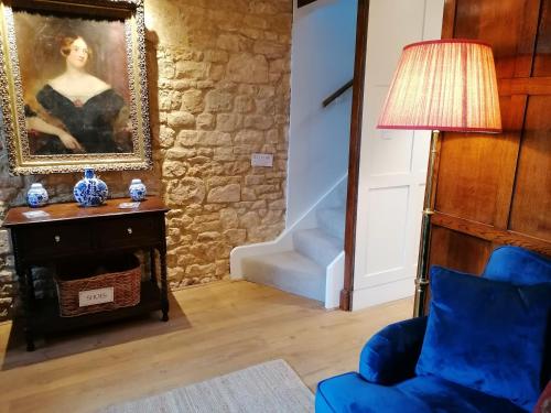una sala de estar con una silla azul y una pintura en Merriman Cottage en Chipping Campden