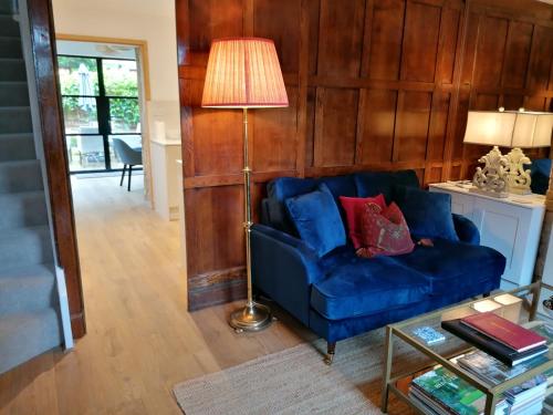 a living room with a blue couch and a lamp at Merriman Cottage in Chipping Campden