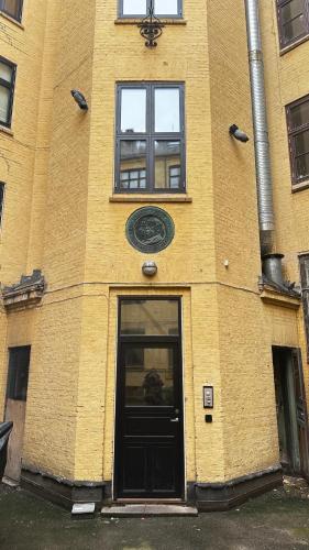 a yellow brick building with a black door at Løvstræde apartments from 1 to 6 in Copenhagen