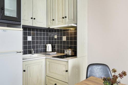 a kitchen with white cabinets and black tiles on the wall at Sunset Premium Studio D in Agios Nikitas