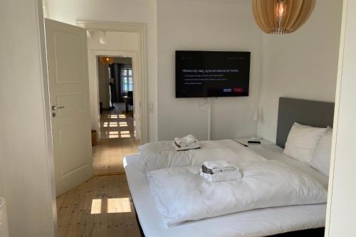 a bedroom with two white beds and a flat screen tv at Harbour View in Sønderborg