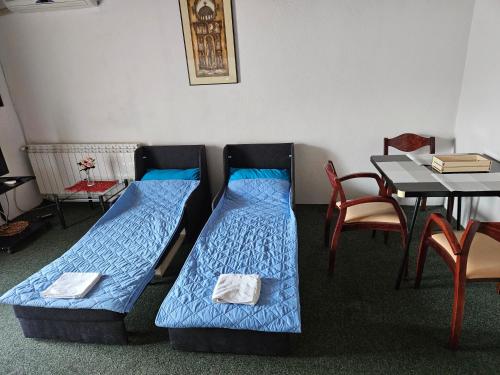 two beds in a room with a table and chairs at VN APARTMENTS OHRID in Ohrid
