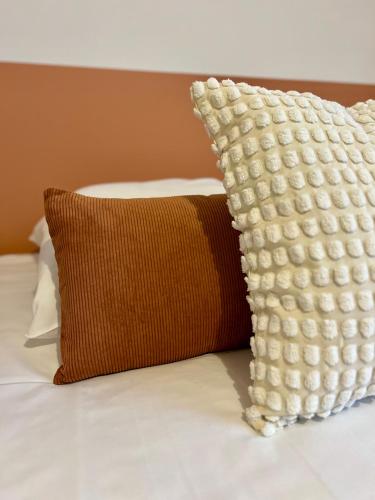 un oreiller posé sur un lit à côté d'un oreiller marron dans l'établissement Le Vitré, Rennes Est, à Rennes