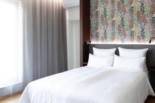 クライルスハイムにあるトップロフト ザ アパートホテルの白いベッド1台付きのベッドルーム1室(壁に絵画付)
