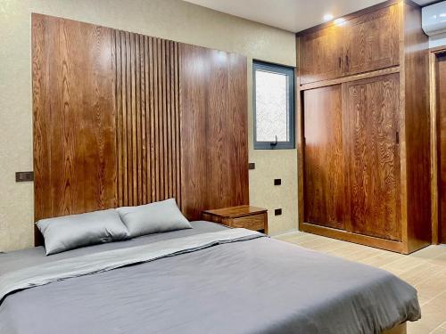1 dormitorio con 1 cama y pared de madera en Green Bay Luxury Villa Sonasea Vân Đồn 