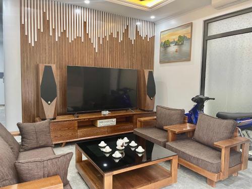 Green Bay Luxury Villa Sonasea Vân Đồn : غرفة معيشة فيها تلفزيون كبير وكراسي وطاولة