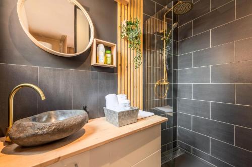 un bagno con un lavandino in pietra e uno specchio di Le Cottage du Louvre a Lens