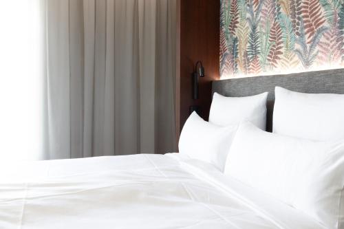a white bed with white sheets and pillows at Toploft The Aparthotel in Crailsheim