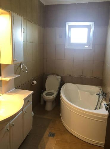 a bathroom with a tub and a toilet and a sink at Eleni house near Asprovalta Ν2 in Néa Kerdhília