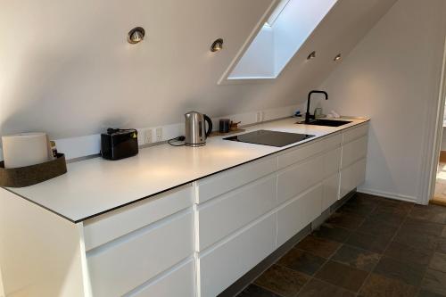 a kitchen with white cabinets and a sink at Sunset Penthouse in Sønderborg