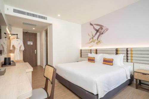 a bedroom with a large white bed and a chair at Pranakorn Heritage Hotel in Bangkok