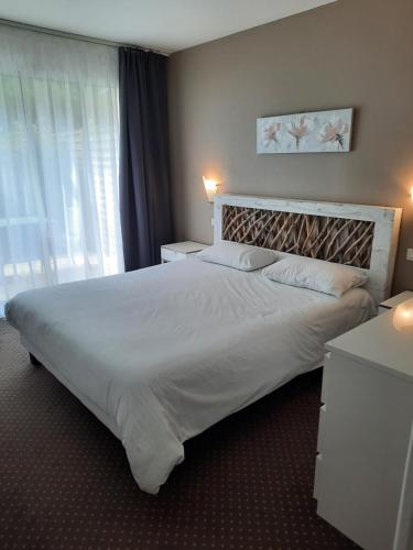 Un dormitorio con una gran cama blanca y una ventana en Appartement AB DU PARC en Neufchâtel-Hardelot