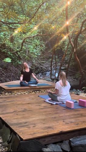 two women sitting on a wooden bridge doing meditation at Meraki Escape in Brevard