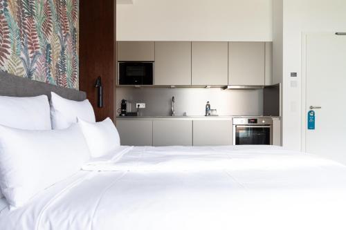 a bedroom with a large white bed and a kitchen at Toploft The Aparthotel in Crailsheim