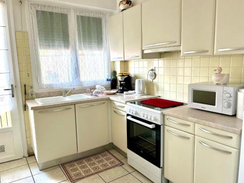 une cuisine avec des armoires blanches, un évier et un micro-ondes dans l'établissement Le Catalogne 3, à Perpignan