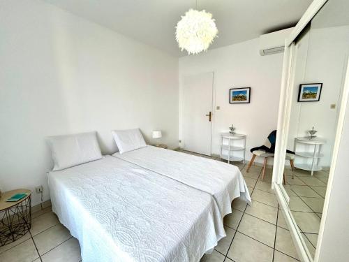 a bedroom with a white bed and a chandelier at Le Catalogne 3 in Perpignan