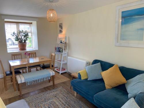 ein Wohnzimmer mit einem blauen Sofa und einem Tisch in der Unterkunft Large 3 bedroom flat in Sennen in Penzance