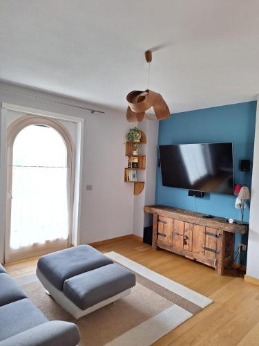 sala de estar con TV de pantalla plana en una pared azul en Aosta Holiday Apartments - Edelweiss, en Aosta