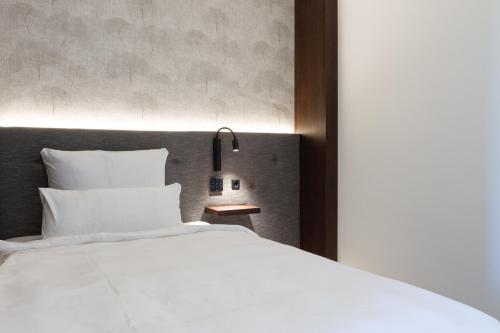 クライルスハイムにあるトップロフト ザ アパートホテルの白い大型ベッドと壁が備わるベッドルーム1室が備わります。