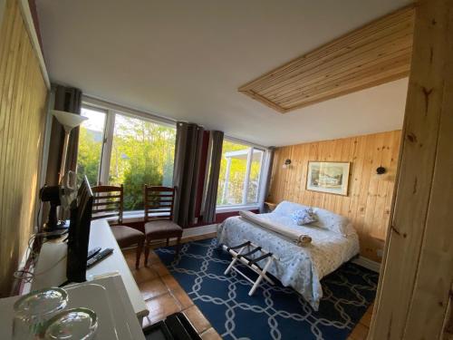 um quarto com uma cama, uma secretária e uma janela em Maison Gauthier em Tadoussac
