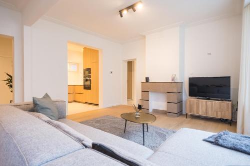 a living room with a couch and a tv at Amandine - Luxury 3 bedrooms apartment with free parking in Ostend
