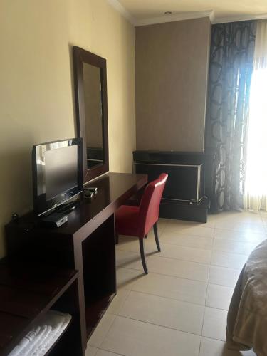 1 dormitorio con escritorio, TV y silla en Faraggi Hotel, en Simvolí