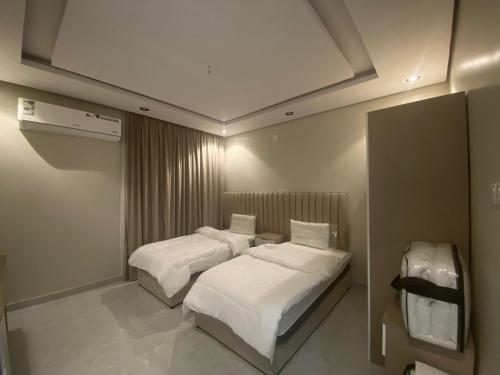 two beds in a small room with white sheets at درة العزيزية للشقق المفروشة in AlUla