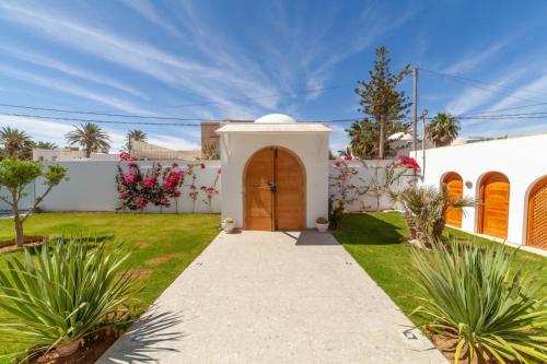a white house with a wooden door in a yard at Villa AZUL in Mezraya