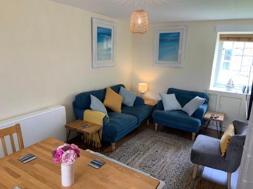 a living room with two blue couches and a table at Large 3 bedroom flat in Sennen in Penzance