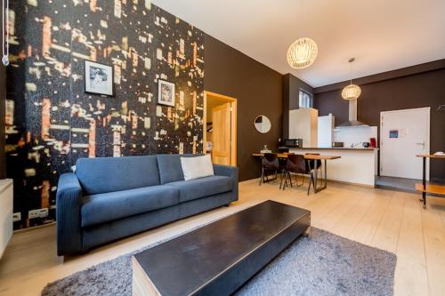 a living room with a blue couch and a kitchen at Smartflats City - Brusselian in Brussels