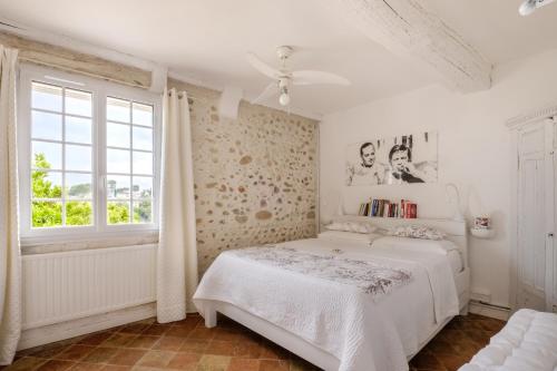 a white bedroom with a bed and a window at Maison de village romantique in Cagnes-sur-Mer