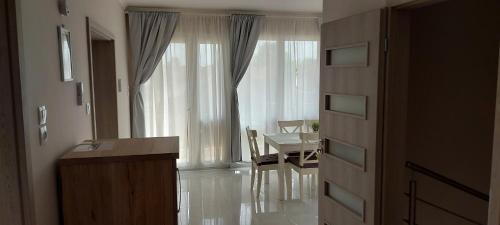 a kitchen and dining room with a table and a window at Relax for you Apartmanház in Cserkeszőlő