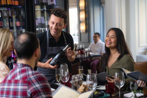 a man holding a bottle of wine in a restaurant at The Gainsborough Bath Spa - Small Luxury Hotels of the World in Bath