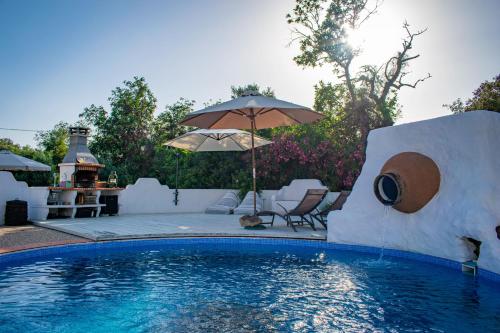 una piscina con ombrellone, sedie e tavolo di Quinta Alcarias a Santa Catarina da Fonte do Bispo