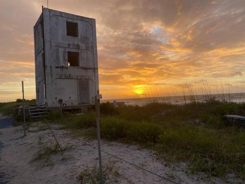 a building on the beach with the sunset in the background at Lil'TipSea on Topsail - Close to the sound and beach! in Topsail Beach
