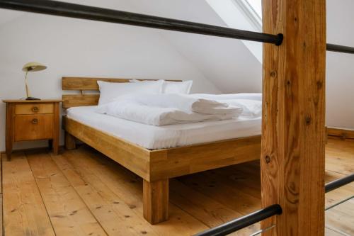 Schlafzimmer mit einem Holzbett mit weißer Bettwäsche in der Unterkunft Roger`s Ferienwohnung in Dießen am Ammersee