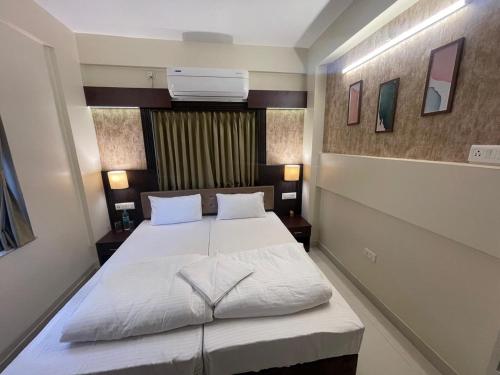 a bedroom with a bed with white sheets and pillows at Chopson's Parc in Thākurdwari