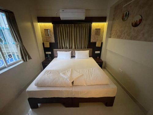 a bedroom with a bed with white sheets and pillows at Chopson's Parc in Thākurdwari